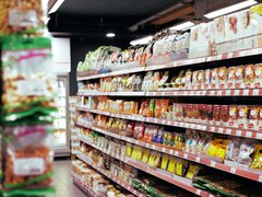 Stock image of a supermarket with aisles of packaged food.