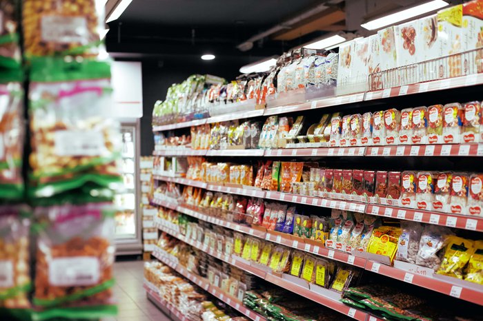 Stock image of a supermarket with aisles of packaged food.