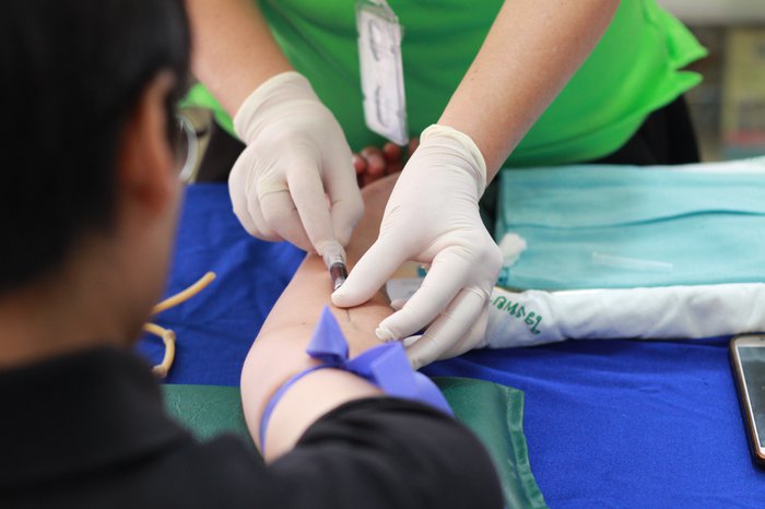 A close up of a person with a needle in their arm giving blood.