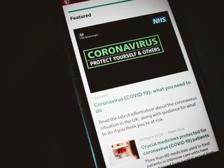 Close-up of a phone screen displaying an official Covid-19 article explaining 'what you need to do' from the NHS and HM Government.