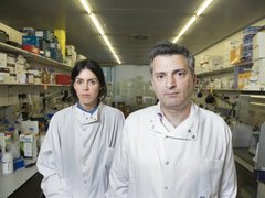 Two scientists pose together in a lab - one female, one male.